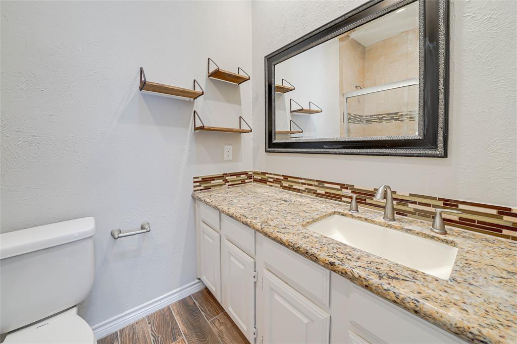 3605 Brown Street, Unit B108 Dallas, TX 75219 - Photo 12 of 18 a bathroom with a granite countertop sink a mirror and a toilet
