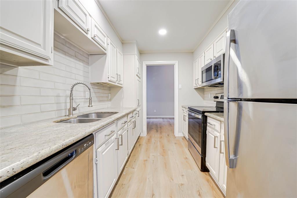 3605 Brown Street, Unit B108 Dallas, TX 75219 - Photo 3 of 18 a kitchen with kitchen island granite countertop a sink stove and refrigerator