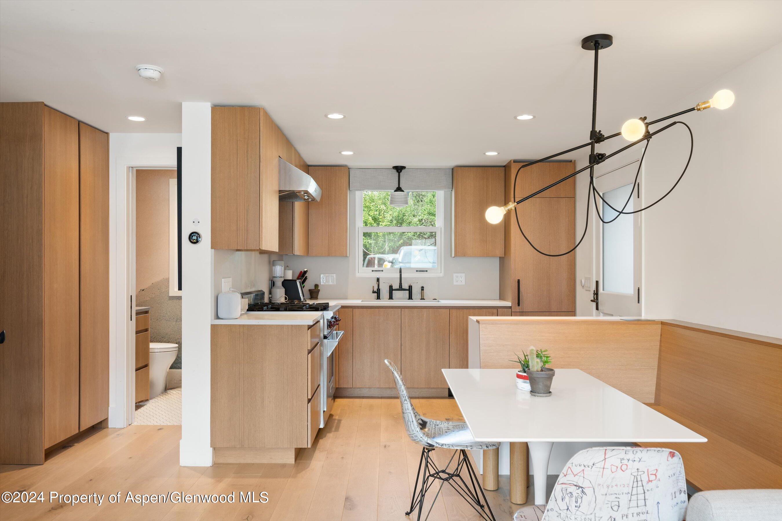 331 West Main Street, Unit B Aspen, CO 81611 - Photo 6 of 21 a kitchen with stainless steel appliances granite countertop a refrigerator a stove and white cabinets with wooden floor