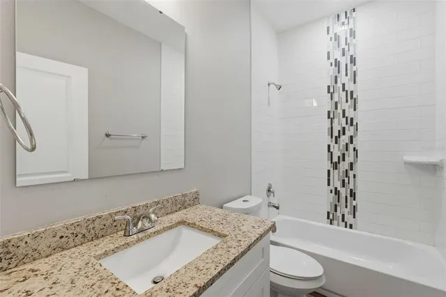 a bathroom with a granite countertop sink a toilet and shower