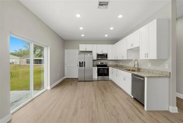 a large kitchen with granite countertop a large counter top stainless steel appliances and cabinets