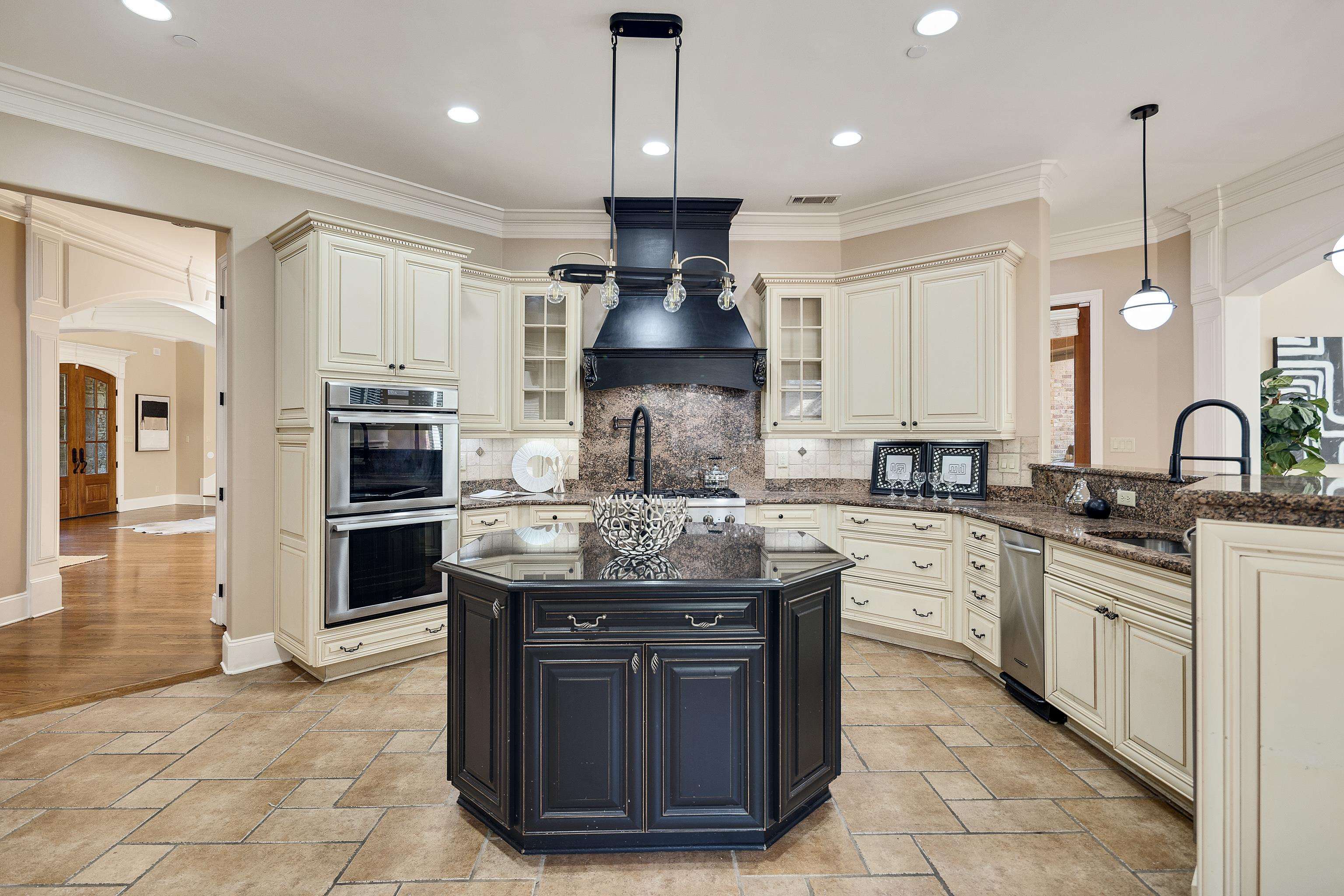 425 Buckland Cove Eads, TN 38028 - Photo 10 of 29 Kitchen with cream cabinetry, arched walkways, dark cabinets, hanging light fixtures, and decorative backsplash