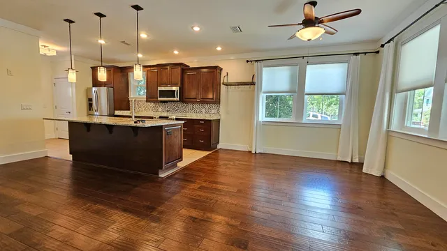 a view of kitchen with stainless steel appliances granite countertop wooden floors and a view of living room