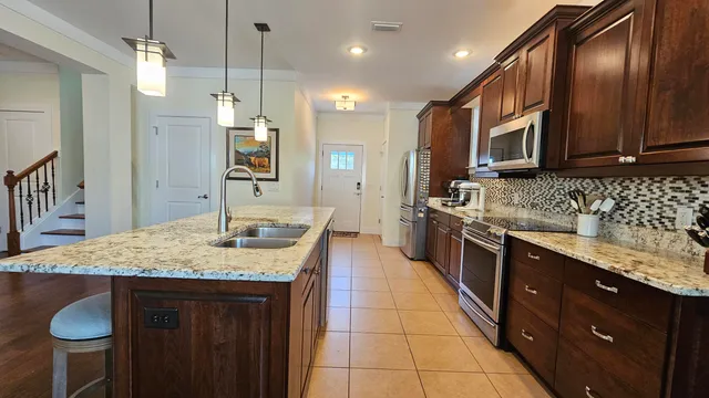 a kitchen with stainless steel appliances granite countertop a sink a stove a refrigerator and a oven