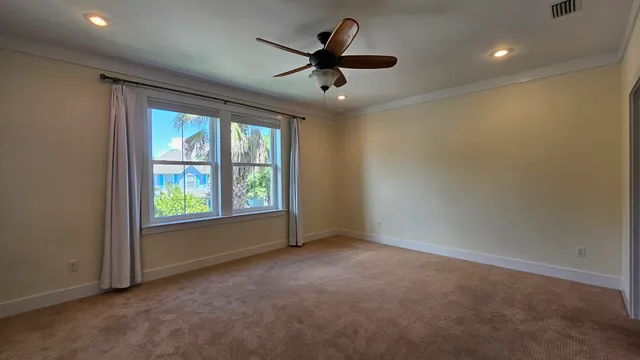 an empty room with windows and ceiling fan