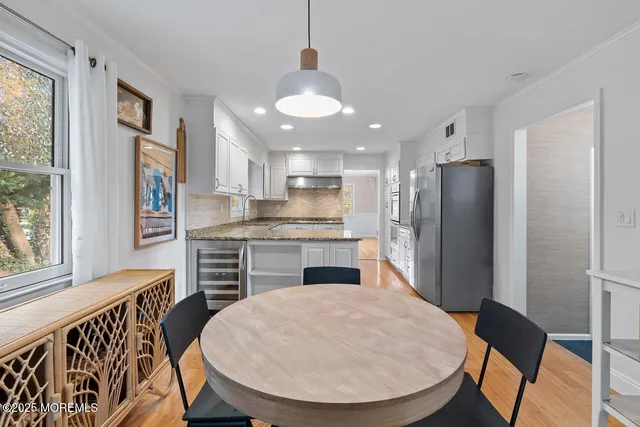 a kitchen with stainless steel appliances granite countertop a refrigerator a stove a sink dishwasher with a dining table and chairs with wooden floor