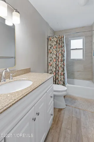 a bathroom with a granite countertop sink a toilet and bathtub