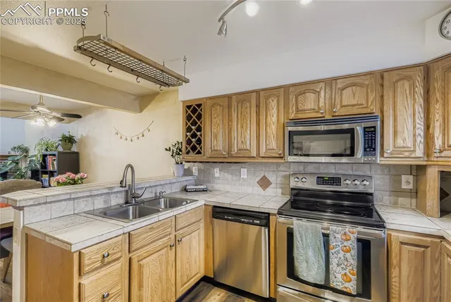 a kitchen with stainless steel appliances a sink a stove a microwave a refrigerator and cabinets