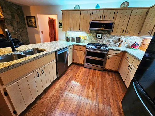 a kitchen with stainless steel appliances a stove top oven a sink and a refrigerator