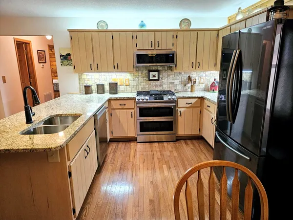 a kitchen with stainless steel appliances granite countertop a refrigerator sink and stove