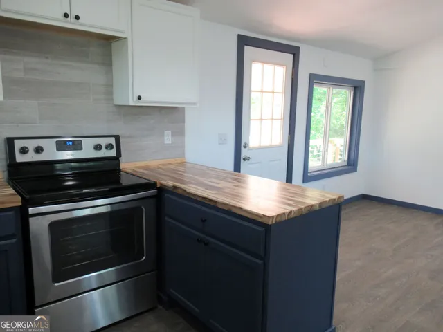 a kitchen with granite countertop cabinets appliances and wooden floor