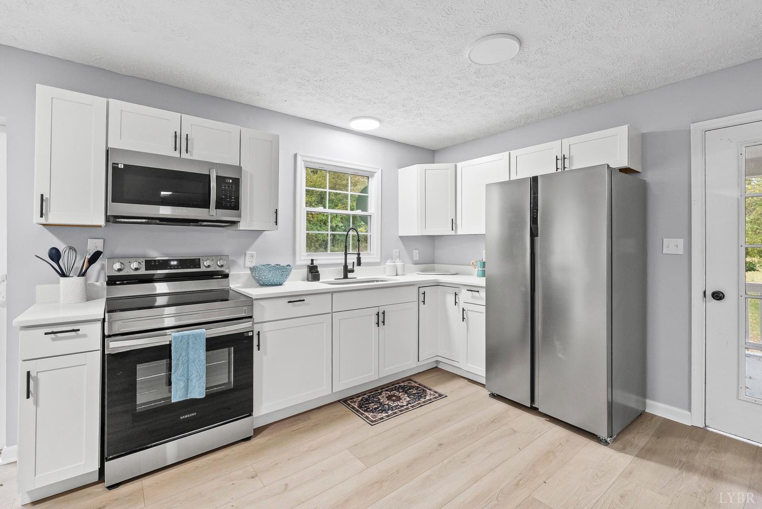 1077 Ringgold Road Ringgold, VA 24586 - Photo 23 of 35 a kitchen with granite countertop a refrigerator stove and microwave