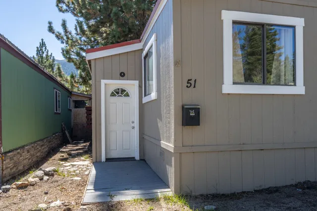 a backyard of a house with table and chairs and potted plants