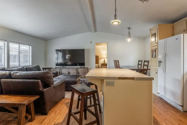 a living room with furniture a flat screen tv and a refrigerator