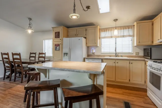 a kitchen with stainless steel appliances granite countertop a stove a refrigerator a kitchen island with chairs and wooden floor