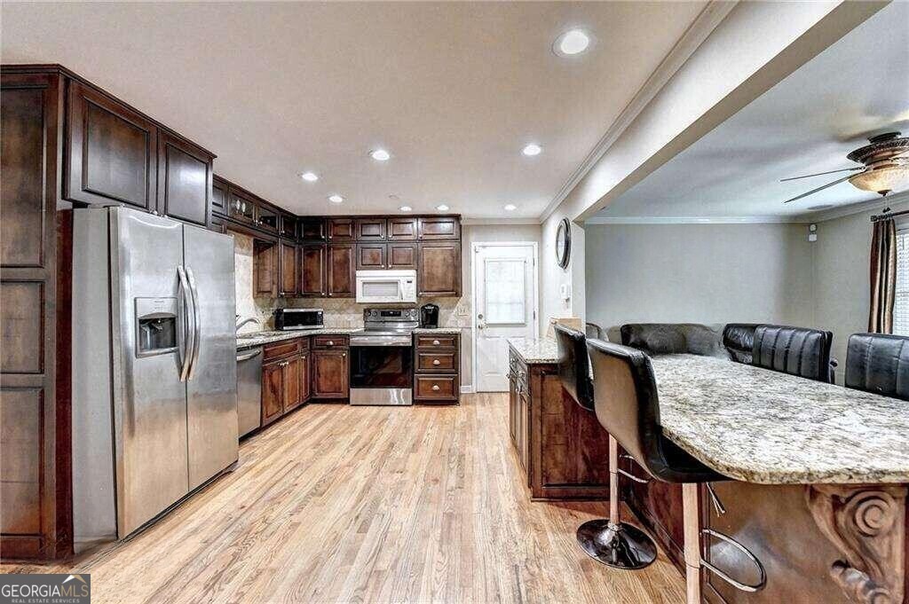 2486 Rex Road Ellenwood, GA 30294 - Photo 3 of 6 a kitchen with granite countertop a refrigerator a stove a sink a dining table and chairs with wooden floor
