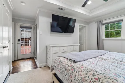 a bedroom with a bed television on desk and a window