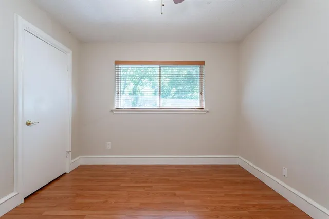 a view of an empty room with wooden floor and a window