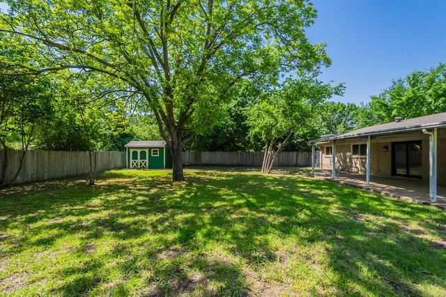 a view of a yard with wooden fence and a large tree