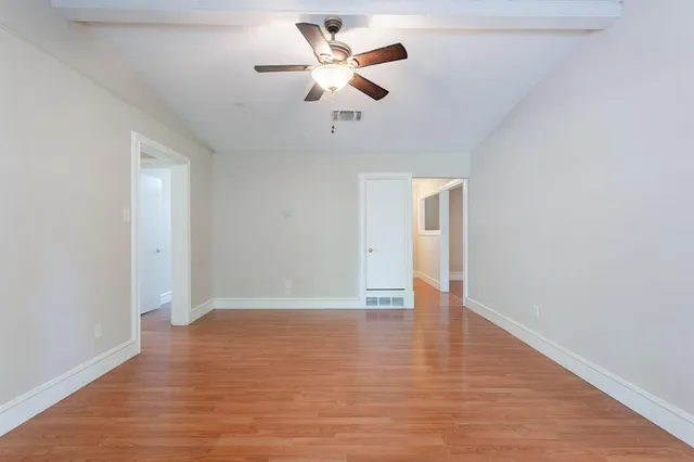 a view of an empty room with window and wooden floor