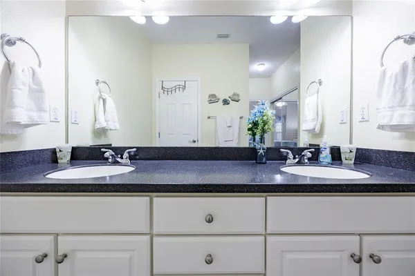 a bathroom with a granite countertop bathtub shower sink vanity and toilet