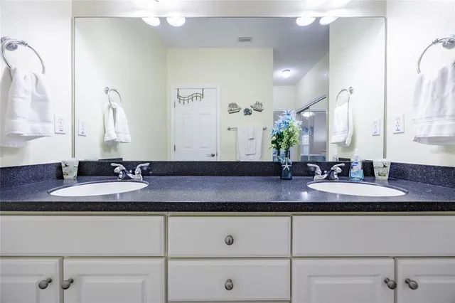 a bathroom with a granite countertop bathtub shower sink vanity and toilet