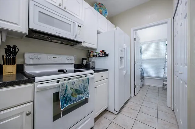 a kitchen with granite countertop white cabinets and white appliances