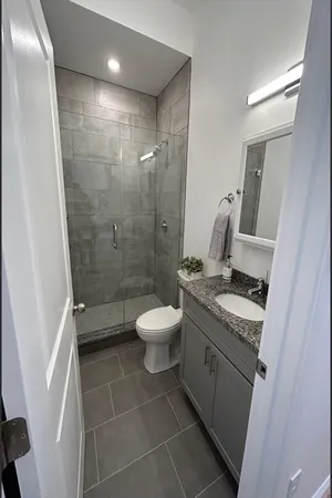 a bathroom with a granite countertop toilet a sink a mirror and a shower