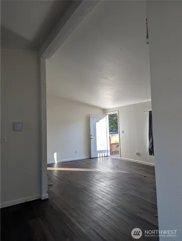 a view of empty room with wooden floor and window