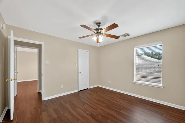 a view of an empty room with a window and wooden floor