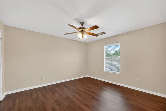 an empty room with wooden floor and ceiling fan
