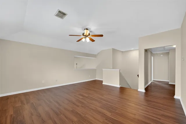 an empty room with wooden floor and ceiling fan