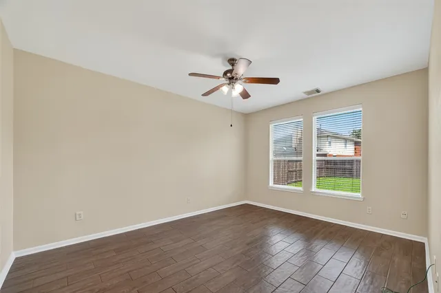 a view of an empty room with a window and wooden floor