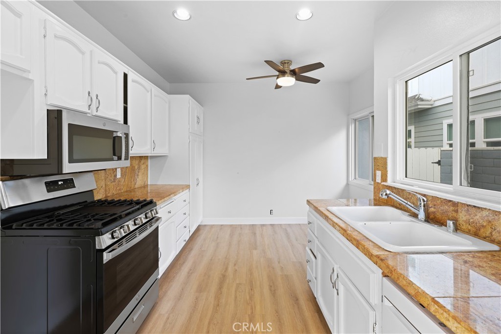 1597 Riverside Place Costa Mesa, CA 92627 - Photo 14 of 37 a kitchen with granite countertop a sink appliances cabinets and a counter top space
