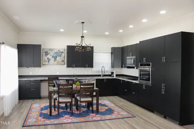 a kitchen with stainless steel appliances granite countertop table chairs sink and stove