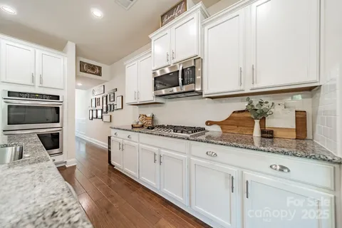 a kitchen with stainless steel appliances granite countertop a stove a sink and a microwave