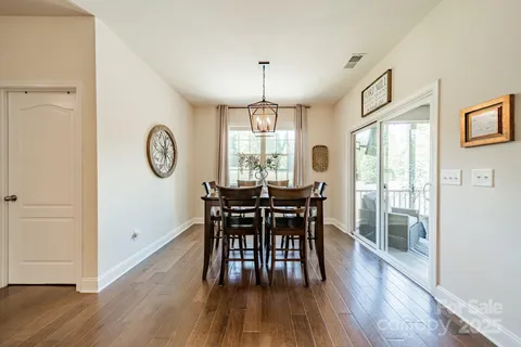 a dining room with wooden floor a chandelier a wooden table and chairs