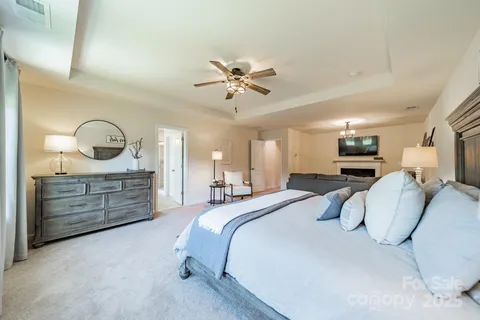 a bedroom with a bed a chandelier and dresser