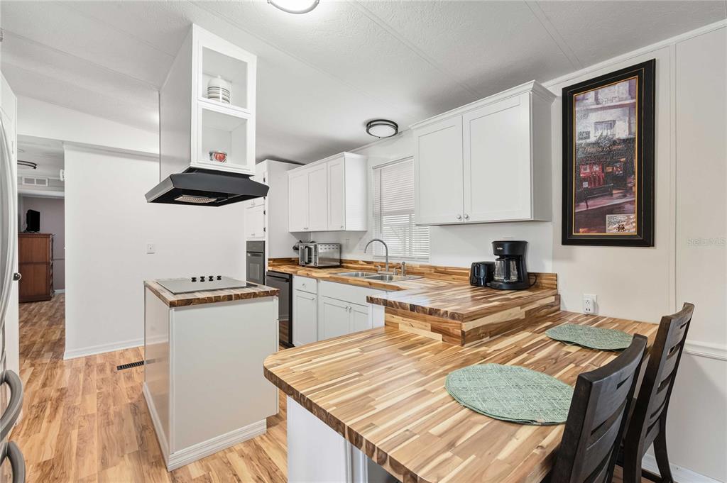 3125 Briar Street Wesley Chapel, FL 33543 - Photo 3 of 42 a kitchen with stainless steel appliances granite countertop a stove top oven a sink a refrigerator and white cabinets with wooden floor