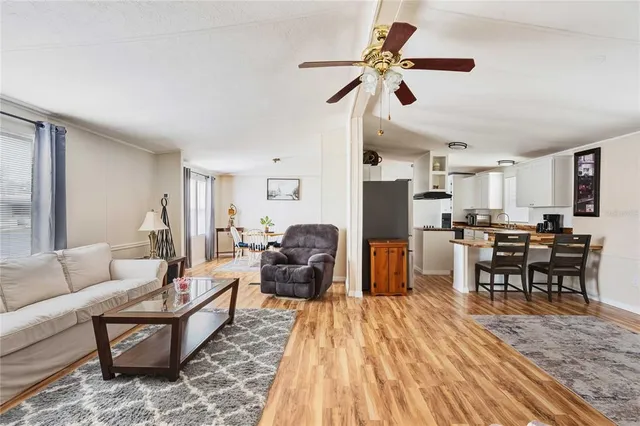 a living room with furniture kitchen view and a wooden floor