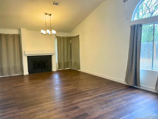 an empty room with wooden floor fireplace and window