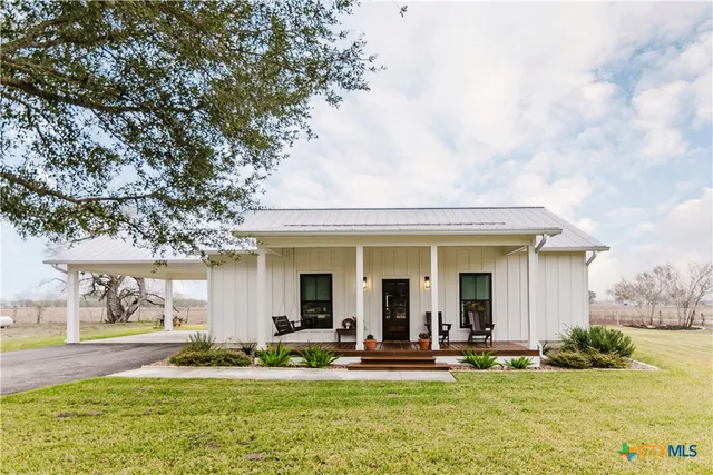 a view of a white house with a big yard and large trees