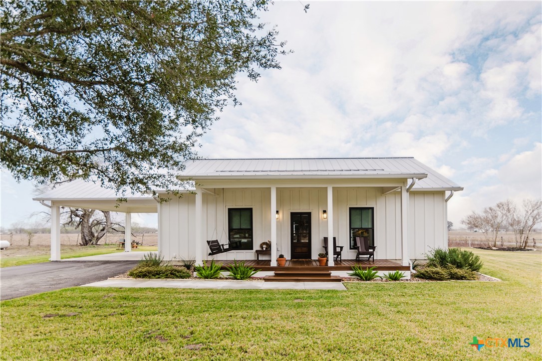 a view of a white house with a big yard and large trees