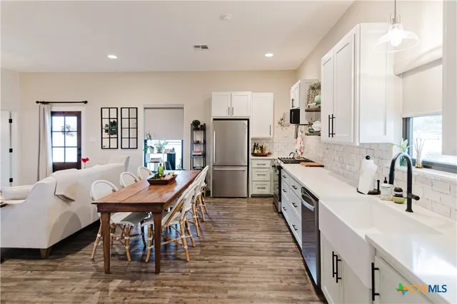 a kitchen with stainless steel appliances a dining table chairs microwave and sink