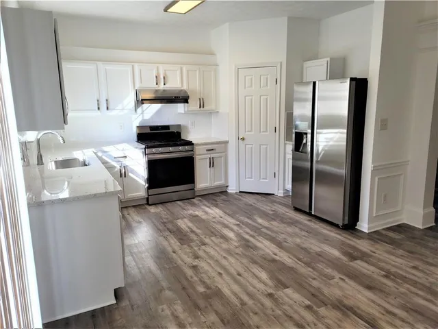 a kitchen with granite countertop a refrigerator and a stove top oven