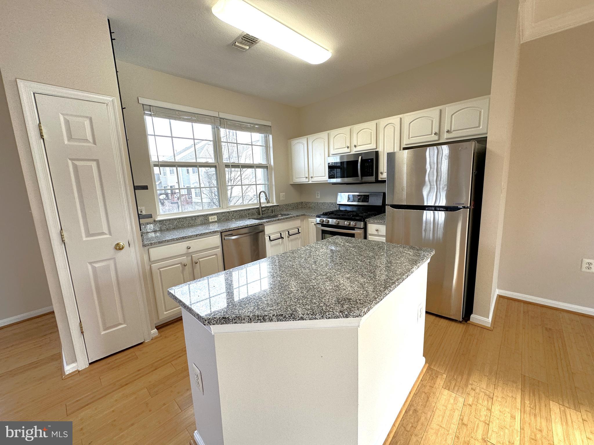 21798 Jarvis Square Ashburn, VA 20147 - Photo 3 of 29 a kitchen with stainless steel appliances granite countertop a sink a microwave a refrigerator and white cabinets