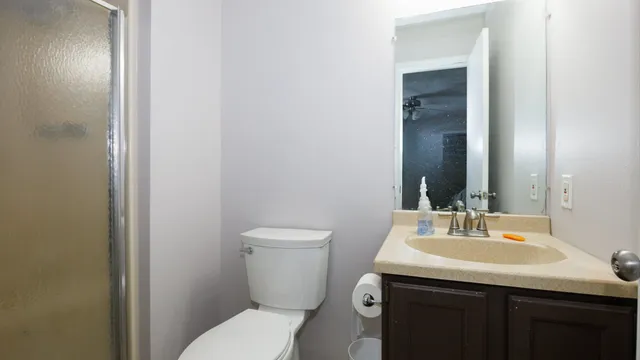 a brick house with a big yard potted plants and large tree