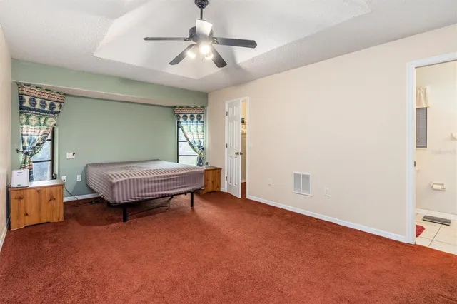 an empty room with windows and ceiling fan