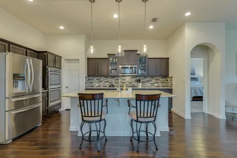 a kitchen with stainless steel appliances granite countertop a refrigerator a stove a sink dishwasher with a dining table and chairs