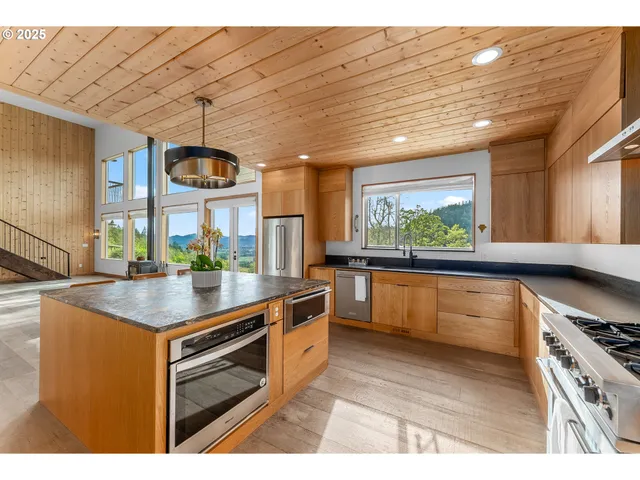 a kitchen with stainless steel appliances granite countertop a sink a stove and a wooden cabinets